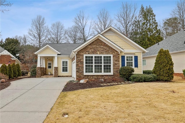 craftsman-style home with stone siding, a front yard, and driveway