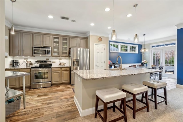 kitchen featuring visible vents, stainless steel appliances, crown molding, a kitchen bar, and backsplash