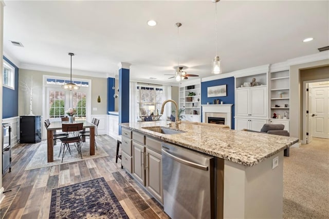 kitchen with dishwasher, a wainscoted wall, built in shelves, a fireplace, and a sink