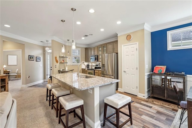 kitchen with a center island with sink, a breakfast bar area, stainless steel appliances, a sink, and recessed lighting