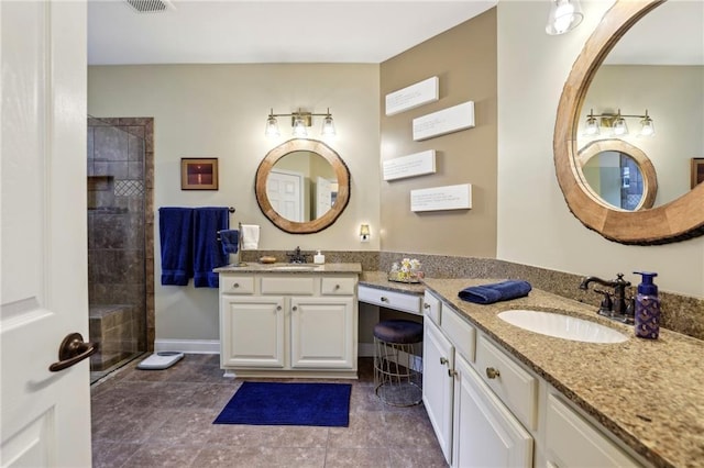 full bath featuring a tile shower, two vanities, a sink, and baseboards