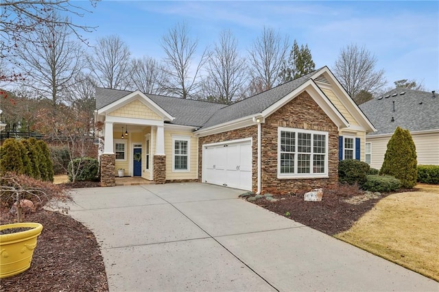 craftsman-style home with driveway, a shingled roof, stone siding, an attached garage, and fence