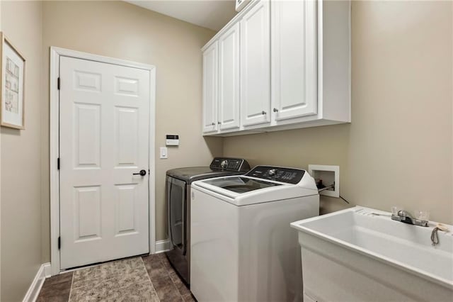 washroom with washer and clothes dryer, a sink, cabinet space, and baseboards