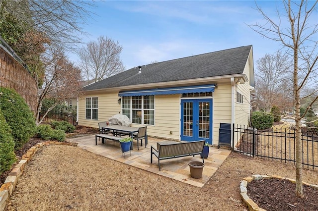 rear view of house with a shingled roof, french doors, a fenced backyard, and a patio