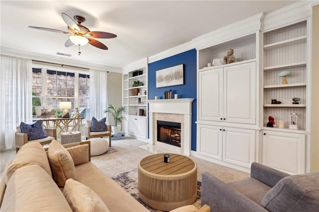 living room with built in features, visible vents, a ceiling fan, light colored carpet, and a fireplace