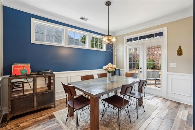 dining space with visible vents, a wainscoted wall, wood tiled floor, crown molding, and french doors