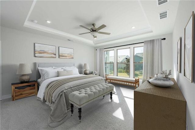 bedroom featuring light colored carpet, a raised ceiling, and ceiling fan