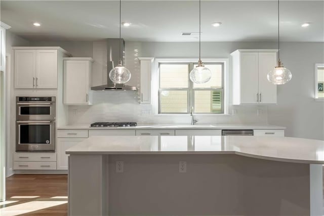 kitchen with white cabinets, pendant lighting, and wall chimney range hood