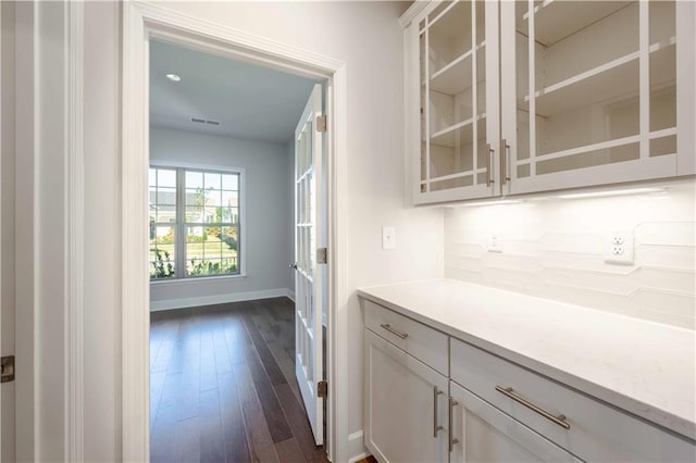 bar with white cabinets, dark hardwood / wood-style floors, and tasteful backsplash