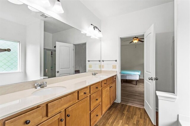 ensuite bathroom featuring a sink, double vanity, wood finished floors, and connected bathroom