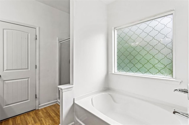 full bath with a shower stall, a bath, and wood finished floors