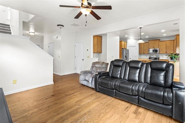 living area featuring a ceiling fan, baseboards, visible vents, and light wood-style flooring