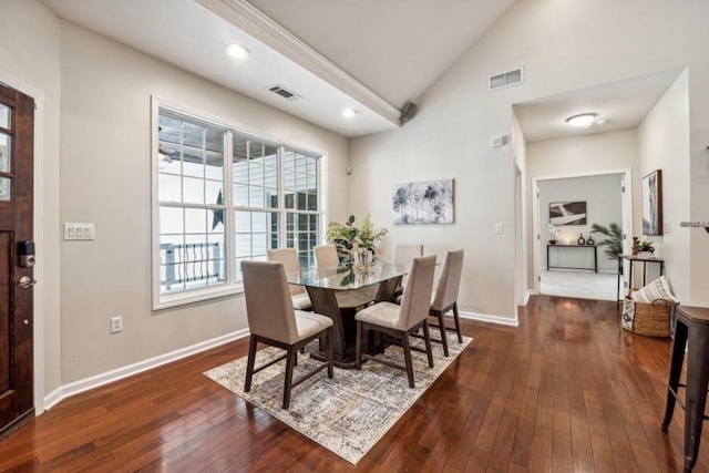 dining room with high vaulted ceiling and dark hardwood / wood-style floors