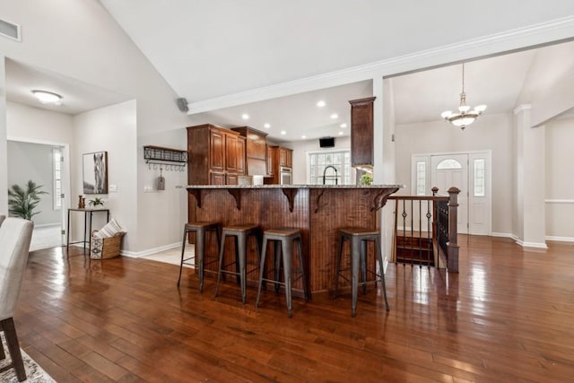 kitchen with lofted ceiling, kitchen peninsula, dark wood-type flooring, and a chandelier