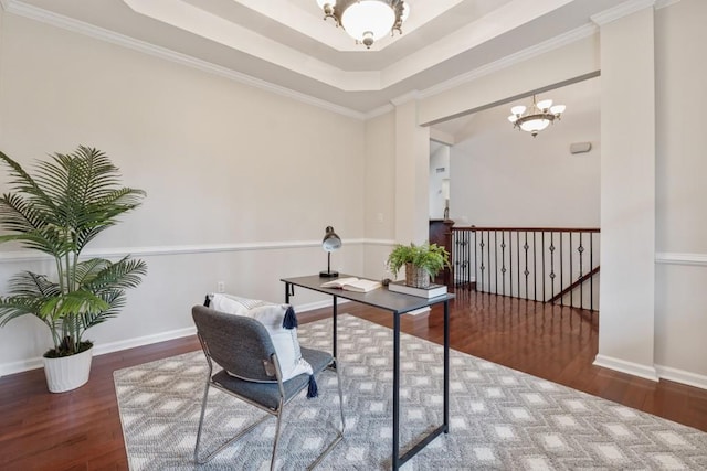 office space featuring dark hardwood / wood-style floors, an inviting chandelier, a tray ceiling, and crown molding