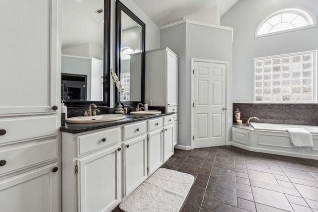 bathroom featuring vanity, a bath, and lofted ceiling