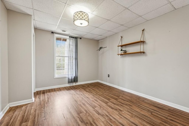 unfurnished room with hardwood / wood-style flooring and a drop ceiling