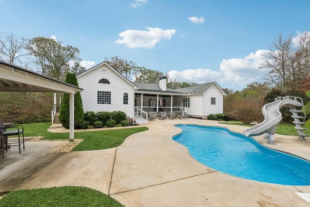 view of pool with a yard, a sunroom, a patio, and a water slide