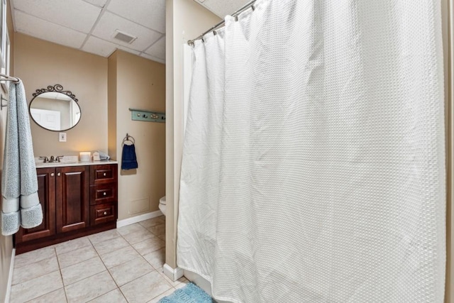 bathroom with a paneled ceiling, tile patterned flooring, vanity, and toilet