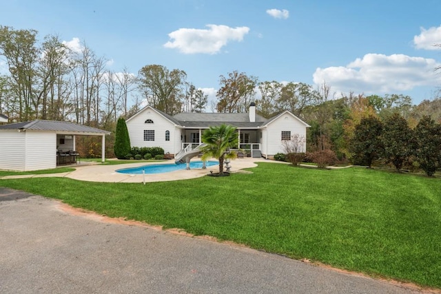 back of property with a lawn, an outbuilding, and a patio