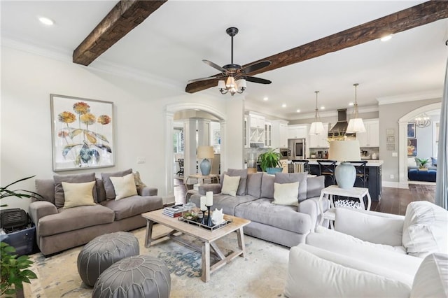 living room with beam ceiling, ceiling fan with notable chandelier, ornamental molding, and light hardwood / wood-style flooring