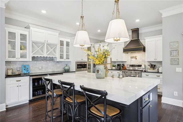 kitchen featuring pendant lighting, white cabinets, stainless steel appliances, wine cooler, and premium range hood