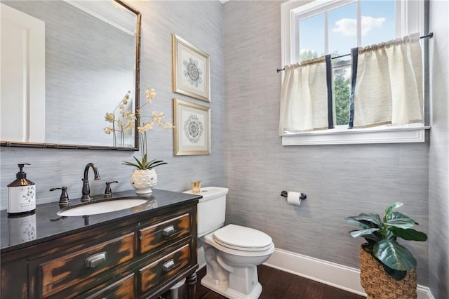 bathroom with toilet, vanity, and hardwood / wood-style floors