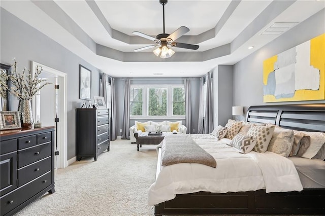 carpeted bedroom featuring a raised ceiling and ceiling fan