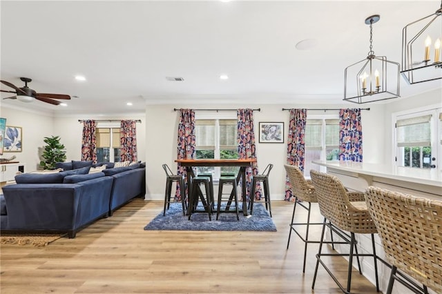 dining space featuring light wood-type flooring, a healthy amount of sunlight, and ceiling fan with notable chandelier