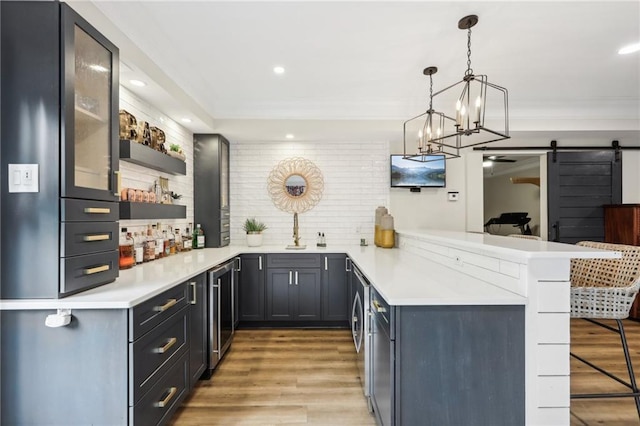 bar featuring a barn door, hardwood / wood-style floors, sink, an inviting chandelier, and hanging light fixtures