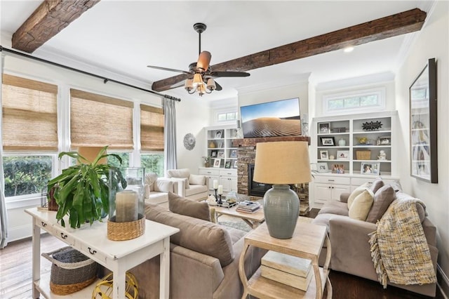 living room with ceiling fan, a fireplace, hardwood / wood-style floors, beamed ceiling, and crown molding