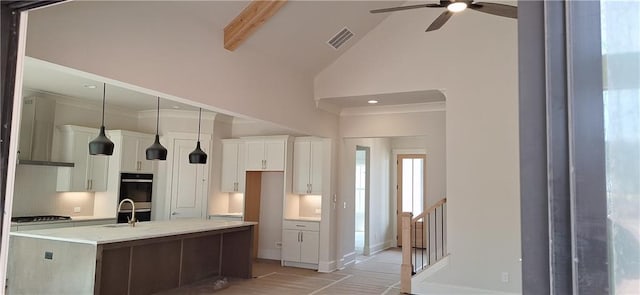 kitchen with sink, hanging light fixtures, light stone counters, an island with sink, and white cabinets