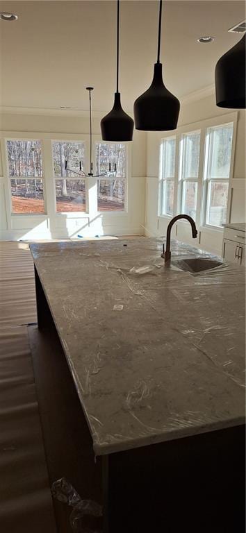 kitchen with light stone countertops, sink, plenty of natural light, and decorative light fixtures