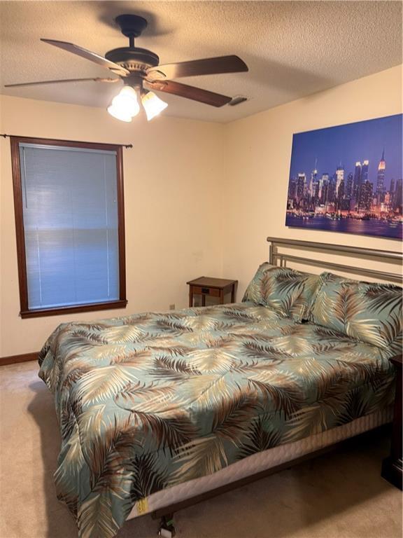 bedroom featuring a city view, a ceiling fan, a textured ceiling, carpet, and baseboards