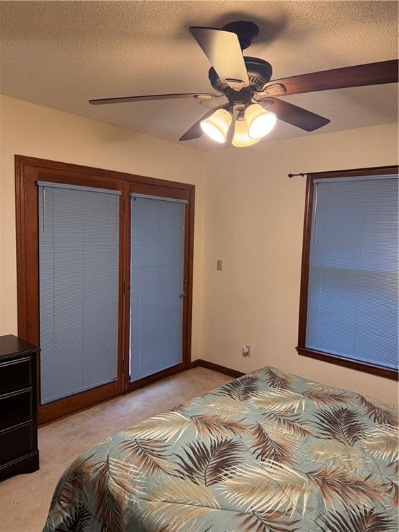 bedroom featuring a textured ceiling, ceiling fan, baseboards, and light carpet