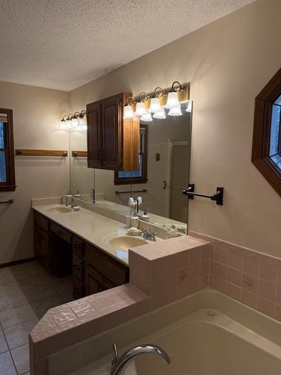 full bath with a sink, a garden tub, a textured ceiling, and tile patterned flooring