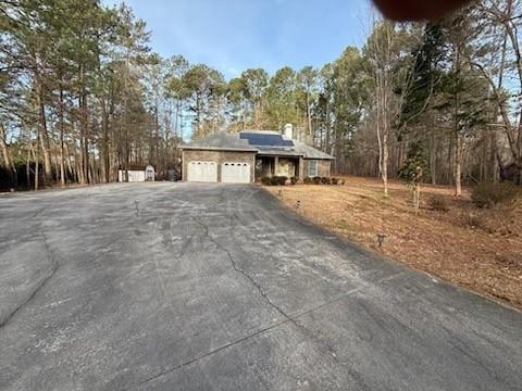 view of front of house featuring aphalt driveway, roof mounted solar panels, and an attached garage