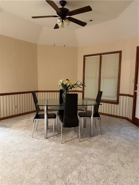 dining area featuring visible vents, baseboards, a wainscoted wall, lofted ceiling, and carpet flooring