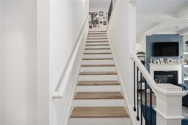 stairs with beam ceiling, coffered ceiling, and a fireplace