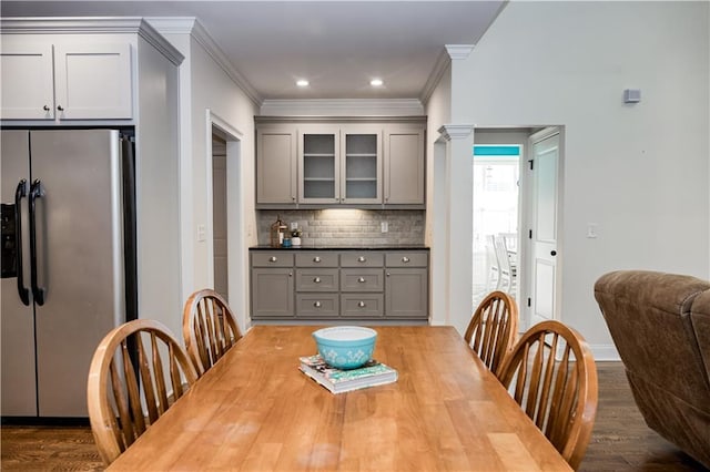 dining space with crown molding, wood-type flooring, and ornate columns