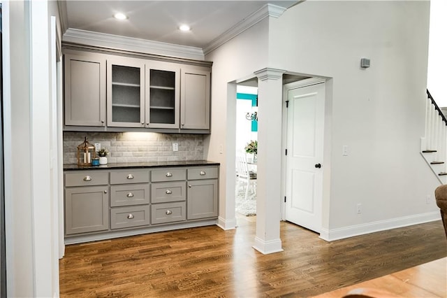 bar featuring ornate columns, tasteful backsplash, gray cabinetry, dark hardwood / wood-style flooring, and ornamental molding