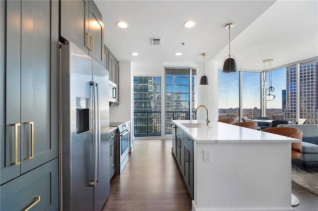 kitchen featuring dark wood-style floors, visible vents, a sink, appliances with stainless steel finishes, and expansive windows