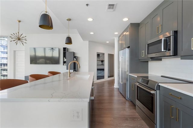 kitchen featuring dark wood-style floors, visible vents, a sink, stainless steel appliances, and tasteful backsplash