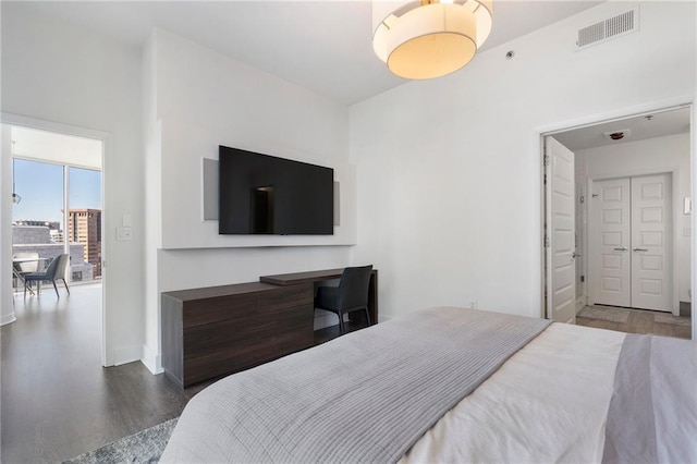 bedroom with visible vents, baseboards, and wood finished floors