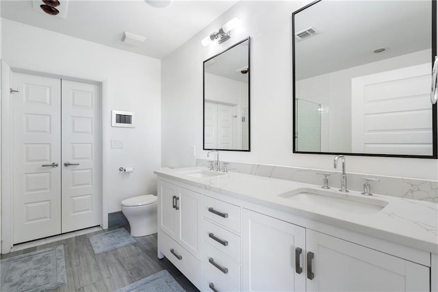 full bath featuring visible vents, toilet, wood finished floors, and a sink