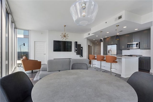 dining area featuring wood finished floors, floor to ceiling windows, recessed lighting, and visible vents
