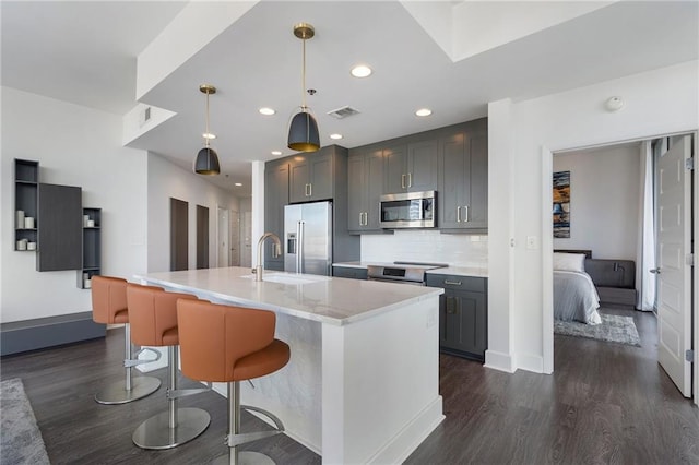 kitchen with visible vents, a sink, backsplash, dark wood-style floors, and stainless steel appliances
