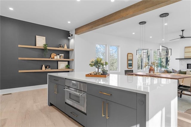 kitchen with gray cabinets, beamed ceiling, hanging light fixtures, a center island, and stainless steel oven