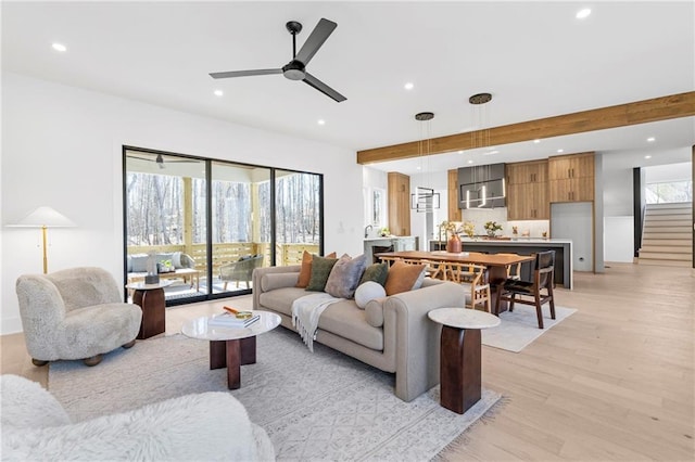 living room with beamed ceiling, ceiling fan, and light hardwood / wood-style flooring