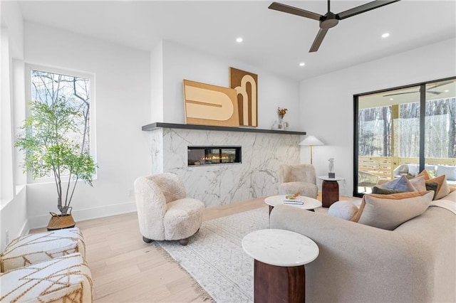 living room with a fireplace, a wealth of natural light, light hardwood / wood-style floors, and ceiling fan